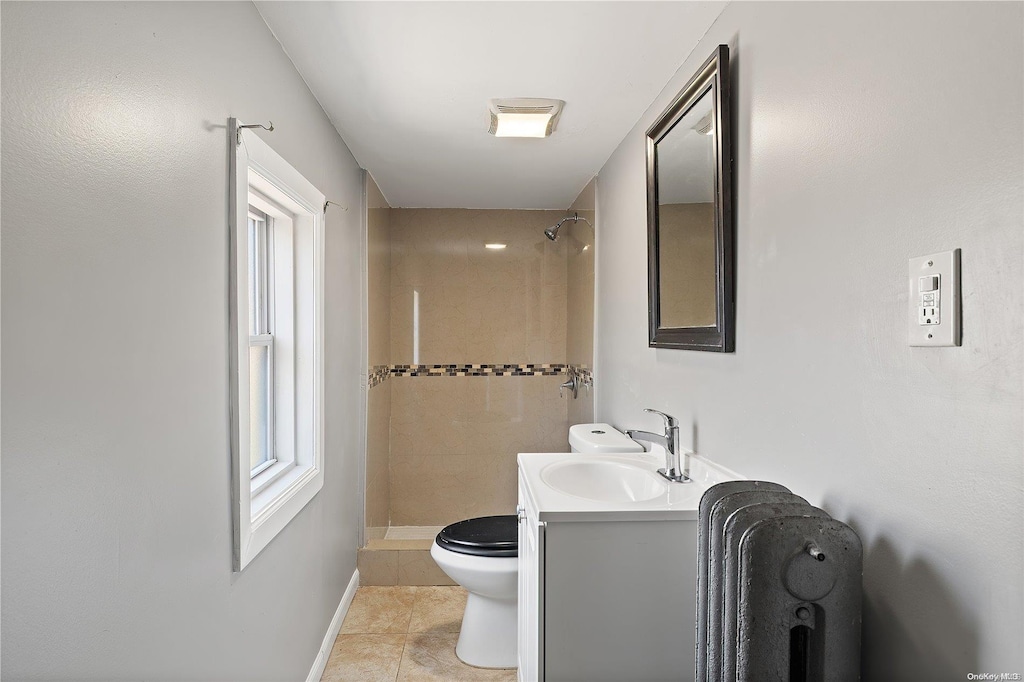 bathroom featuring tiled shower, vanity, tile patterned floors, and toilet