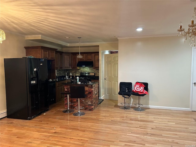 kitchen with light hardwood / wood-style flooring, pendant lighting, a breakfast bar area, black fridge with ice dispenser, and stainless steel stove