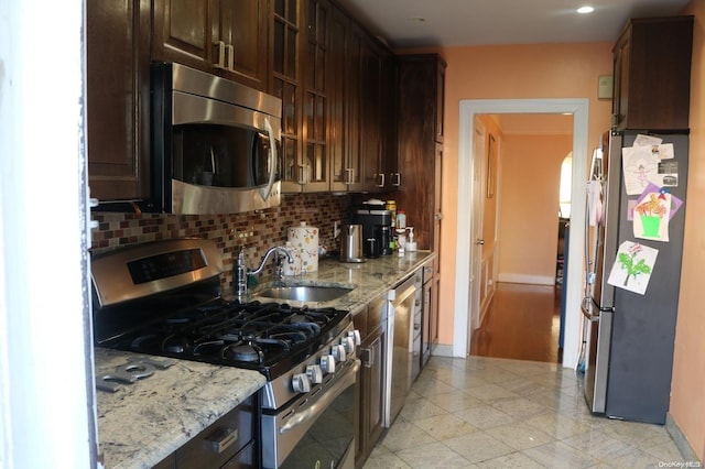 kitchen with tasteful backsplash, light stone counters, dark brown cabinets, and stainless steel appliances