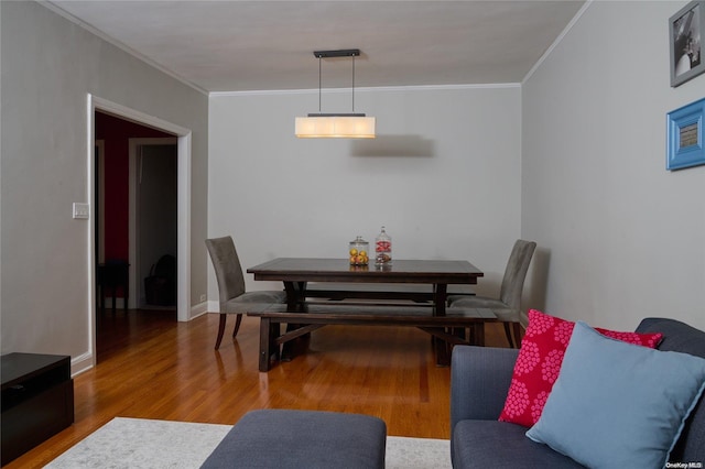 dining space with wood-type flooring and ornamental molding