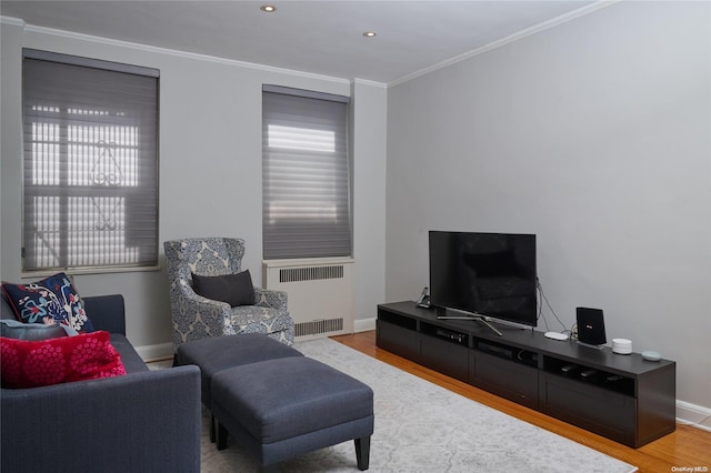 living room featuring radiator, ornamental molding, and light wood-type flooring