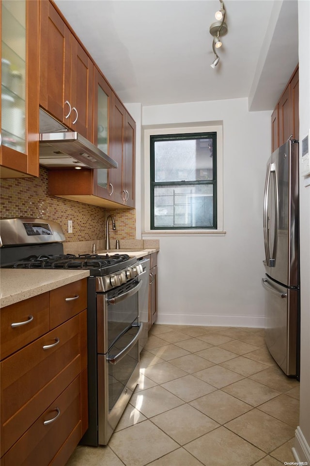 kitchen with decorative backsplash, light stone counters, light tile patterned floors, and stainless steel appliances