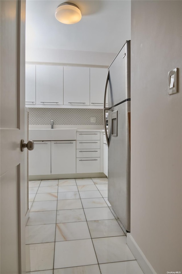 kitchen with stainless steel fridge, backsplash, and white cabinetry