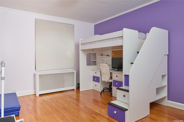 bedroom featuring light wood-type flooring, radiator heating unit, and crown molding