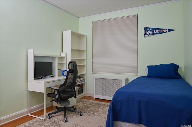 bedroom featuring light wood-type flooring, radiator heating unit, and ornamental molding