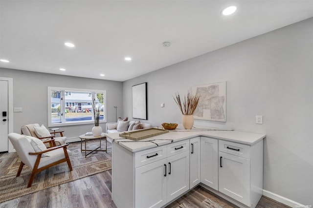 kitchen with kitchen peninsula, wood-type flooring, and white cabinetry