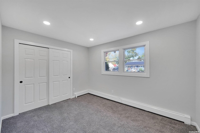 unfurnished bedroom with carpet flooring, a closet, and a baseboard radiator