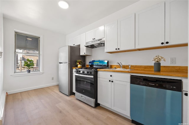 kitchen with light wood-type flooring, appliances with stainless steel finishes, white cabinets, and sink