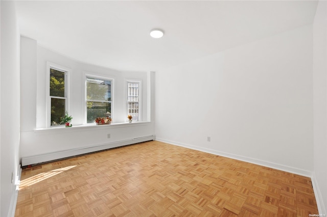 spare room featuring a baseboard heating unit and light parquet floors