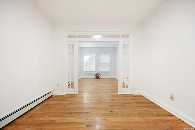 unfurnished room featuring a baseboard radiator and light hardwood / wood-style flooring