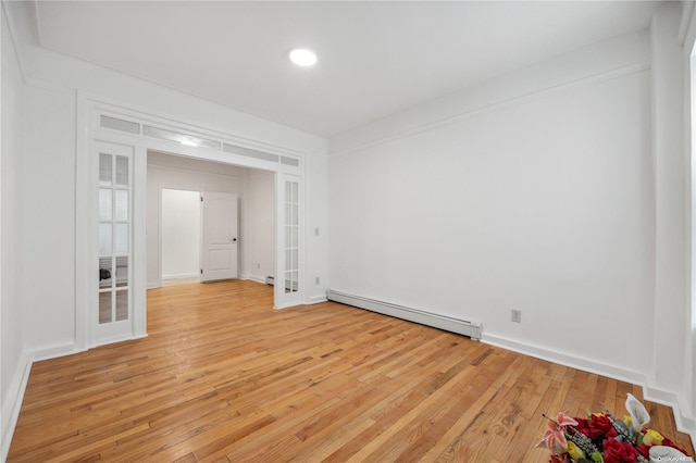 spare room with baseboard heating, french doors, and light hardwood / wood-style flooring