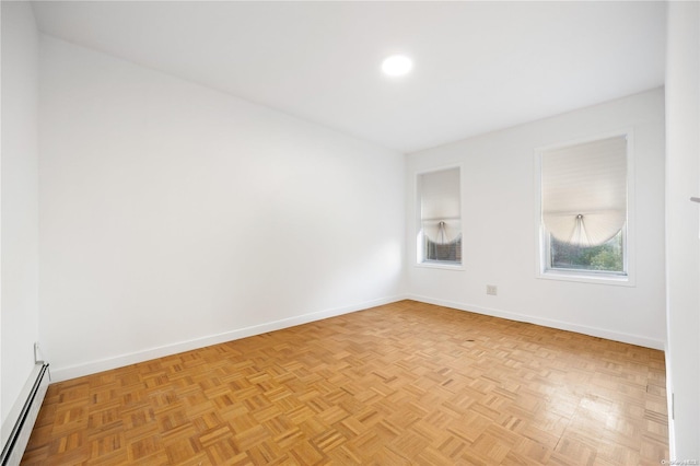 unfurnished room with light parquet flooring and a baseboard radiator