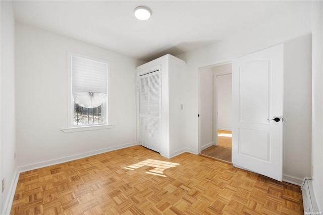 unfurnished bedroom with baseboard heating and light parquet floors