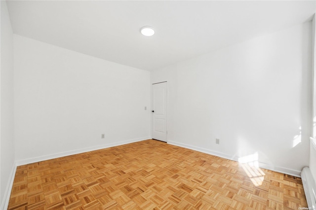 empty room with light parquet flooring and a baseboard heating unit