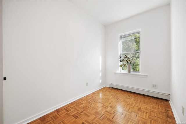 spare room featuring a baseboard radiator and light parquet flooring