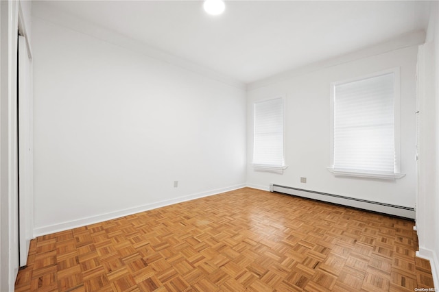 empty room with baseboard heating, crown molding, and light parquet flooring