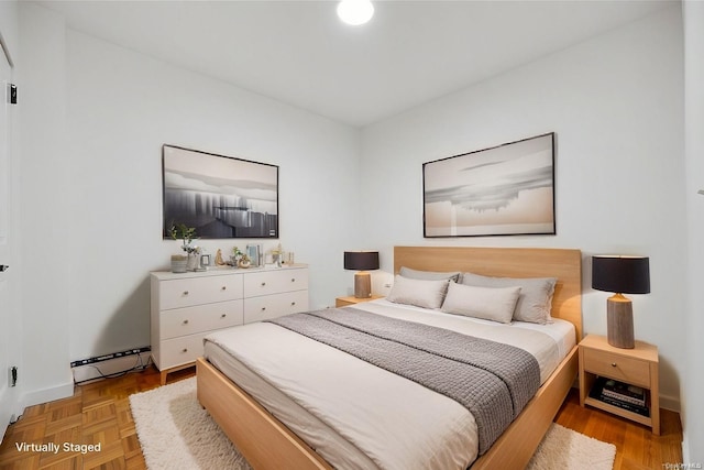 bedroom featuring a baseboard heating unit and light parquet floors