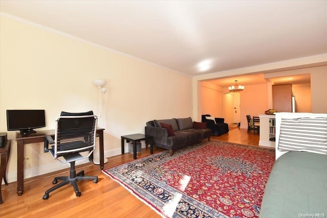 living room with hardwood / wood-style flooring, an inviting chandelier, and crown molding