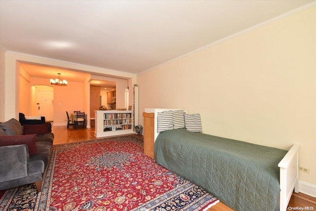 bedroom with crown molding, wood-type flooring, and an inviting chandelier