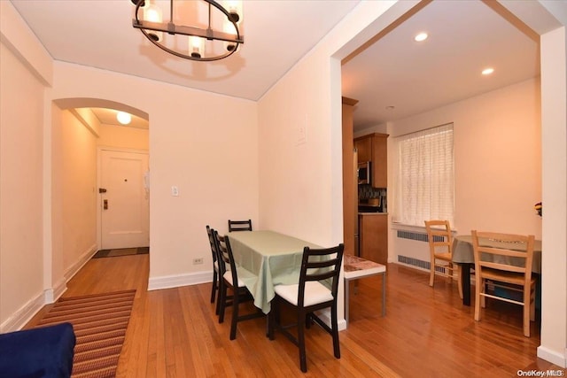 dining area with radiator heating unit, light wood-type flooring, and a notable chandelier