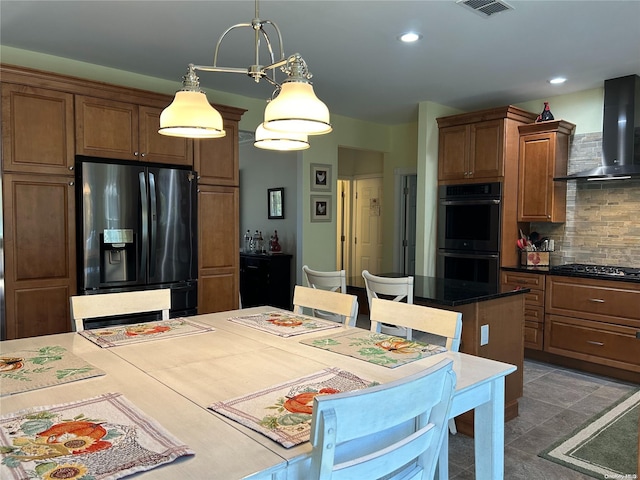 kitchen featuring decorative backsplash, appliances with stainless steel finishes, wall chimney exhaust hood, decorative light fixtures, and a center island