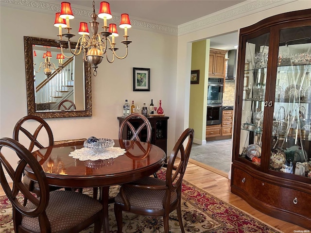 dining room featuring light wood-type flooring, an inviting chandelier, and crown molding