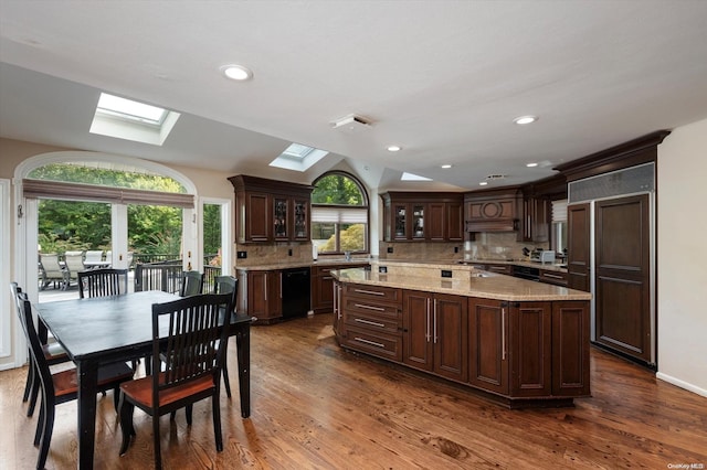 kitchen with backsplash, lofted ceiling with skylight, dark brown cabinets, and dark wood-type flooring