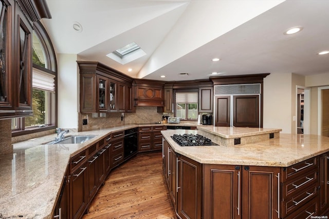 kitchen featuring paneled built in refrigerator, hardwood / wood-style floors, lofted ceiling with skylight, and light stone countertops