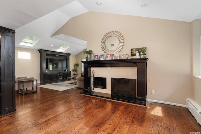 living room featuring a tile fireplace, lofted ceiling with skylight, a baseboard radiator, and hardwood / wood-style flooring