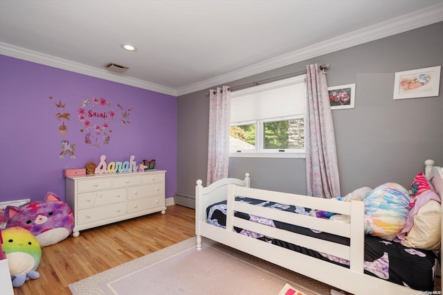 bedroom with ornamental molding, a baseboard heating unit, and hardwood / wood-style flooring