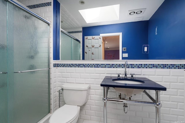 bathroom with sink, a skylight, toilet, tile walls, and an enclosed shower