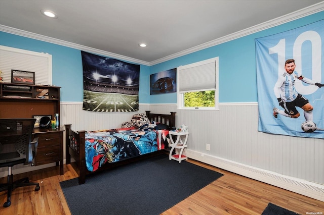 bedroom with baseboard heating, hardwood / wood-style floors, and ornamental molding