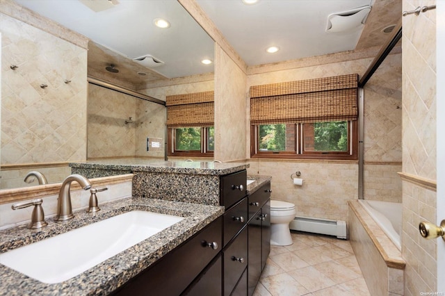 full bathroom with tiled shower / bath combo, baseboard heating, toilet, vanity, and tile walls