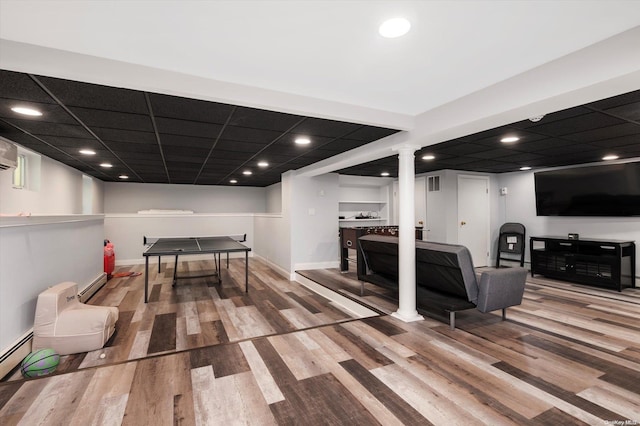 recreation room with a drop ceiling, wood-type flooring, and baseboard heating