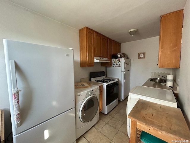 kitchen featuring light tile patterned floors, white appliances, washer / clothes dryer, and sink