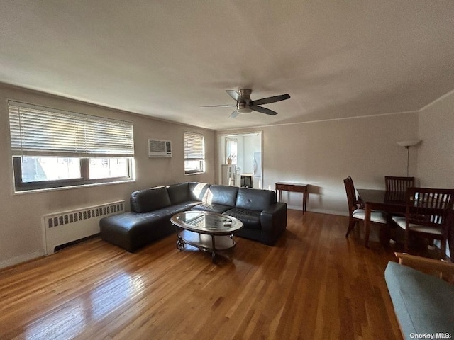 living room featuring a wall mounted AC, ceiling fan, radiator heating unit, and wood-type flooring