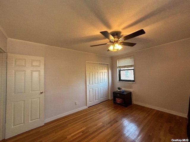 unfurnished bedroom with a closet, dark hardwood / wood-style floors, ceiling fan, and ornamental molding