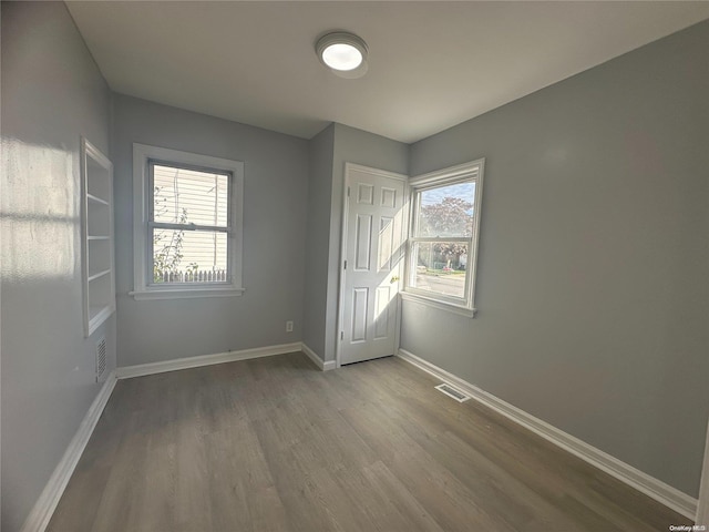 empty room with hardwood / wood-style flooring and a healthy amount of sunlight