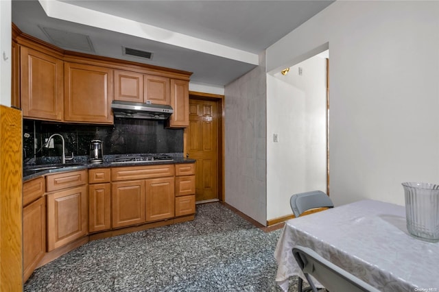 kitchen featuring dark stone countertops, decorative backsplash, sink, and stainless steel gas stovetop