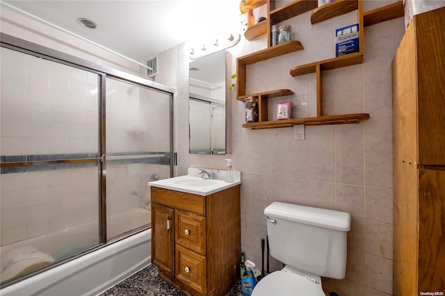 full bathroom featuring vanity, enclosed tub / shower combo, tile walls, and toilet