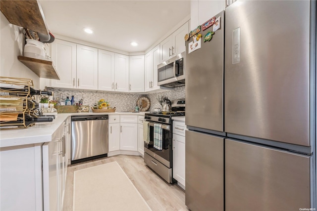 kitchen featuring backsplash, white cabinetry, light wood-type flooring, and appliances with stainless steel finishes