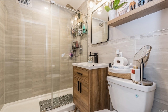 bathroom with walk in shower, vanity, tile walls, and toilet