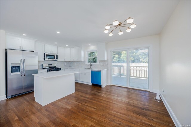 kitchen featuring a center island, dark wood-type flooring, tasteful backsplash, white cabinets, and appliances with stainless steel finishes