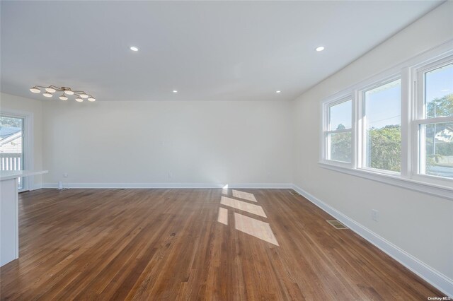 empty room with dark hardwood / wood-style flooring and a wealth of natural light