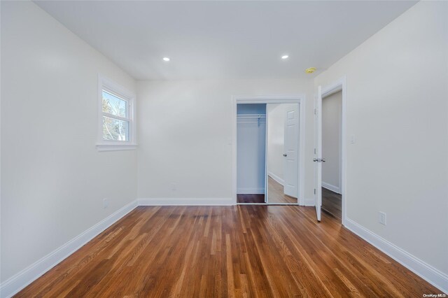 unfurnished bedroom with dark hardwood / wood-style floors and a closet