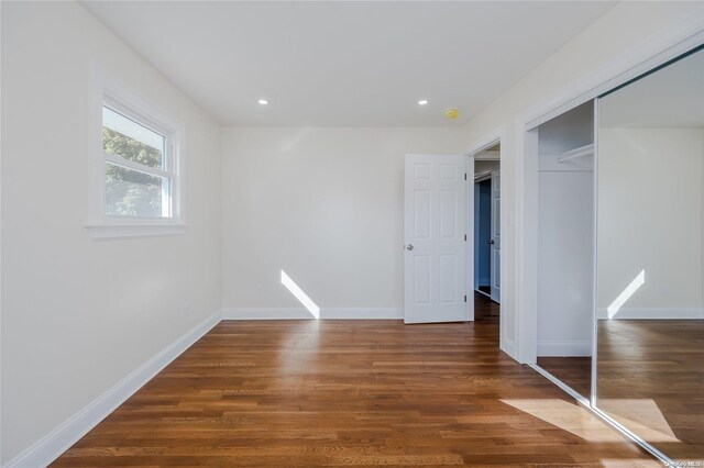 unfurnished bedroom featuring a closet and dark wood-type flooring