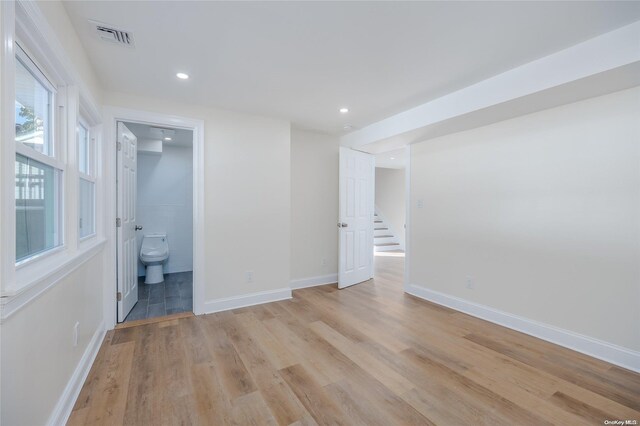 unfurnished bedroom featuring ensuite bathroom and light hardwood / wood-style floors