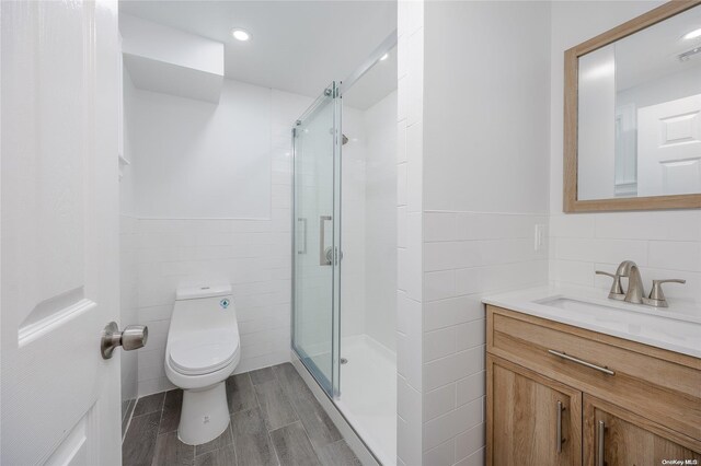 bathroom with walk in shower, toilet, vanity, tile walls, and hardwood / wood-style flooring