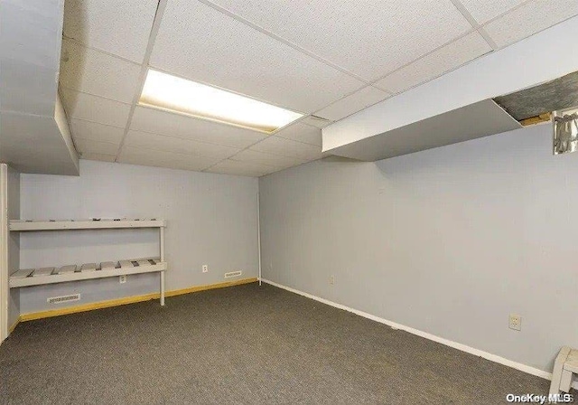 basement with dark colored carpet and a paneled ceiling