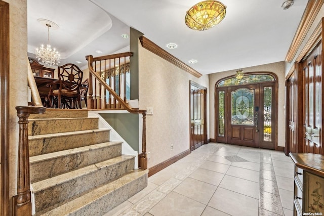 tiled entryway featuring crown molding, a healthy amount of sunlight, and a notable chandelier